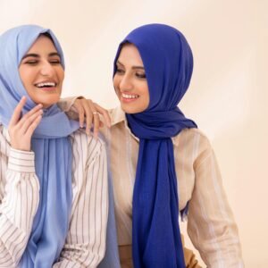 About Cheerful women in blue hijabs enjoying a light moment indoors.